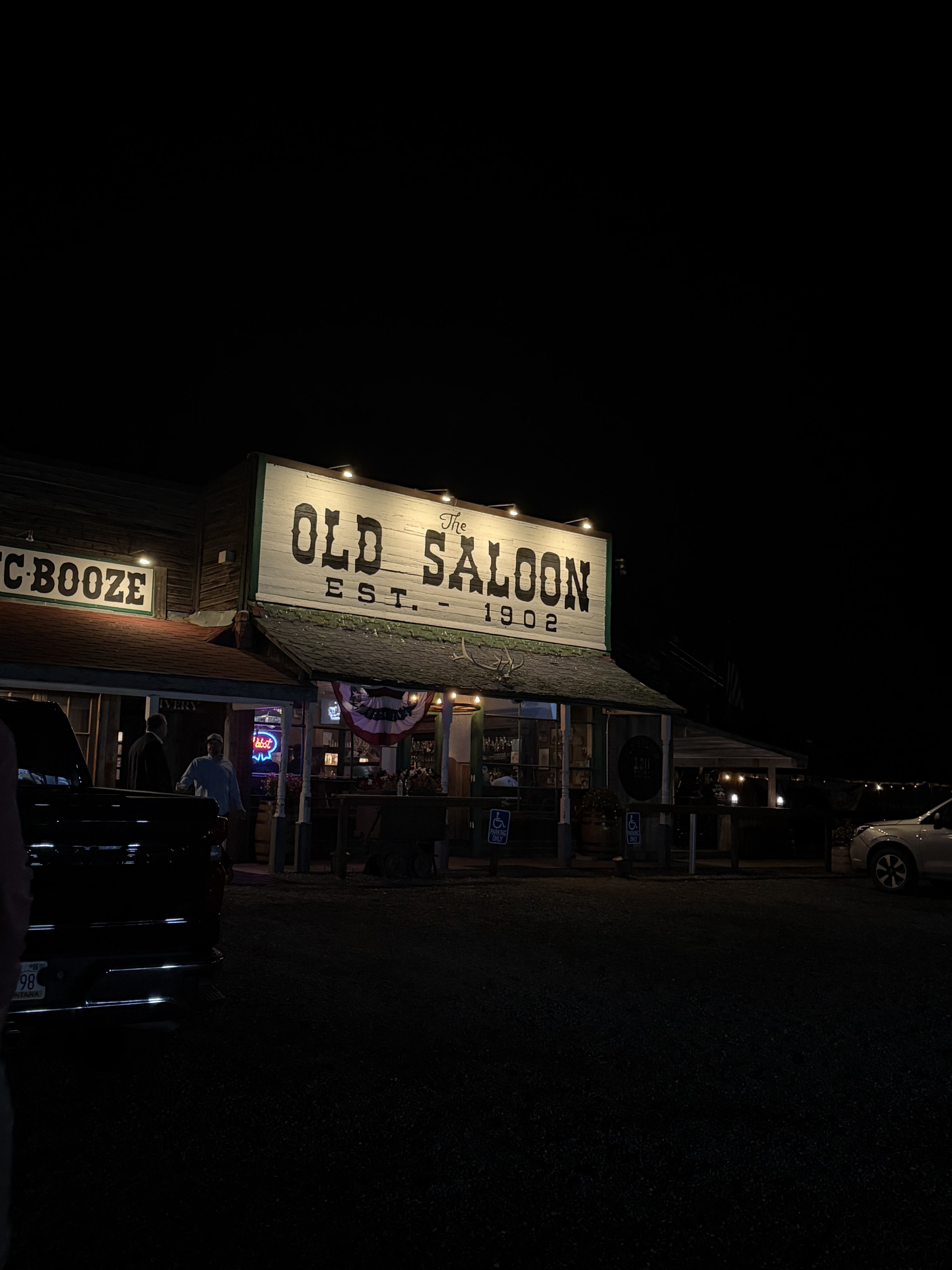 The Old Saloon's wooden sign glowing at night