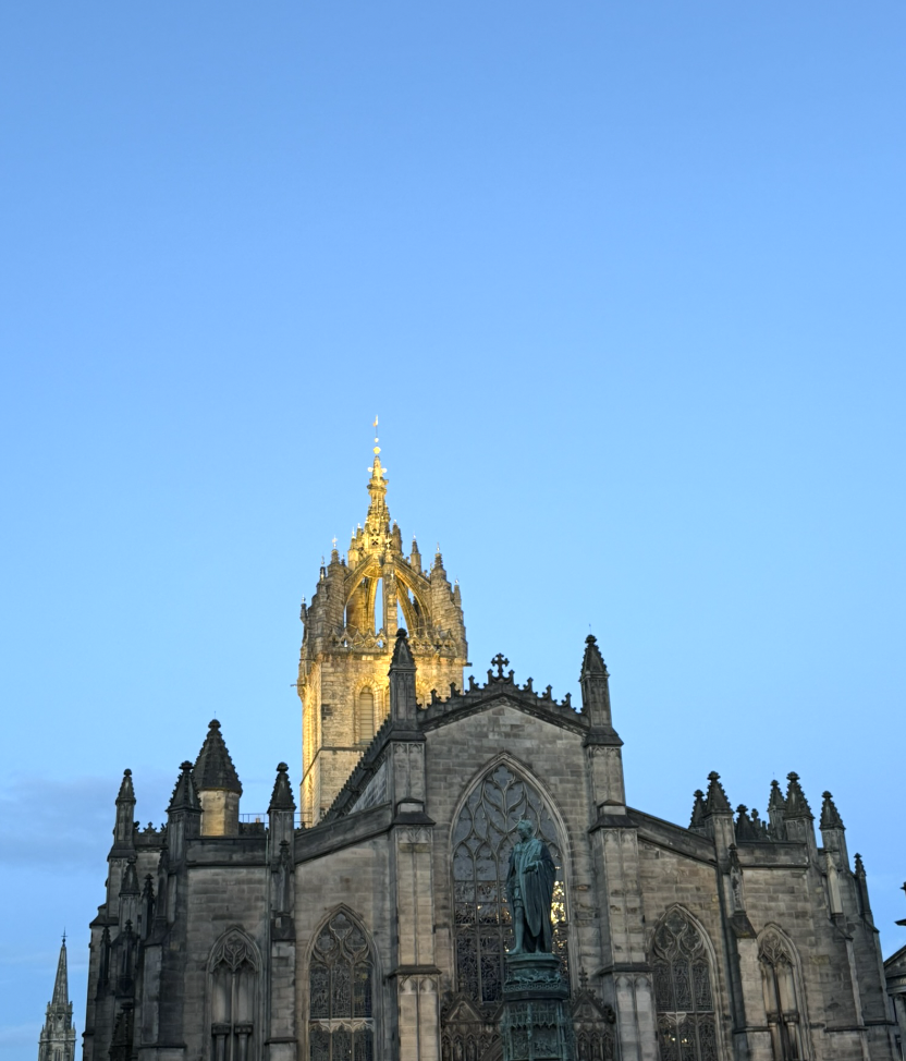 An illuminated ornate church façade against Edinburgh's evening sky
