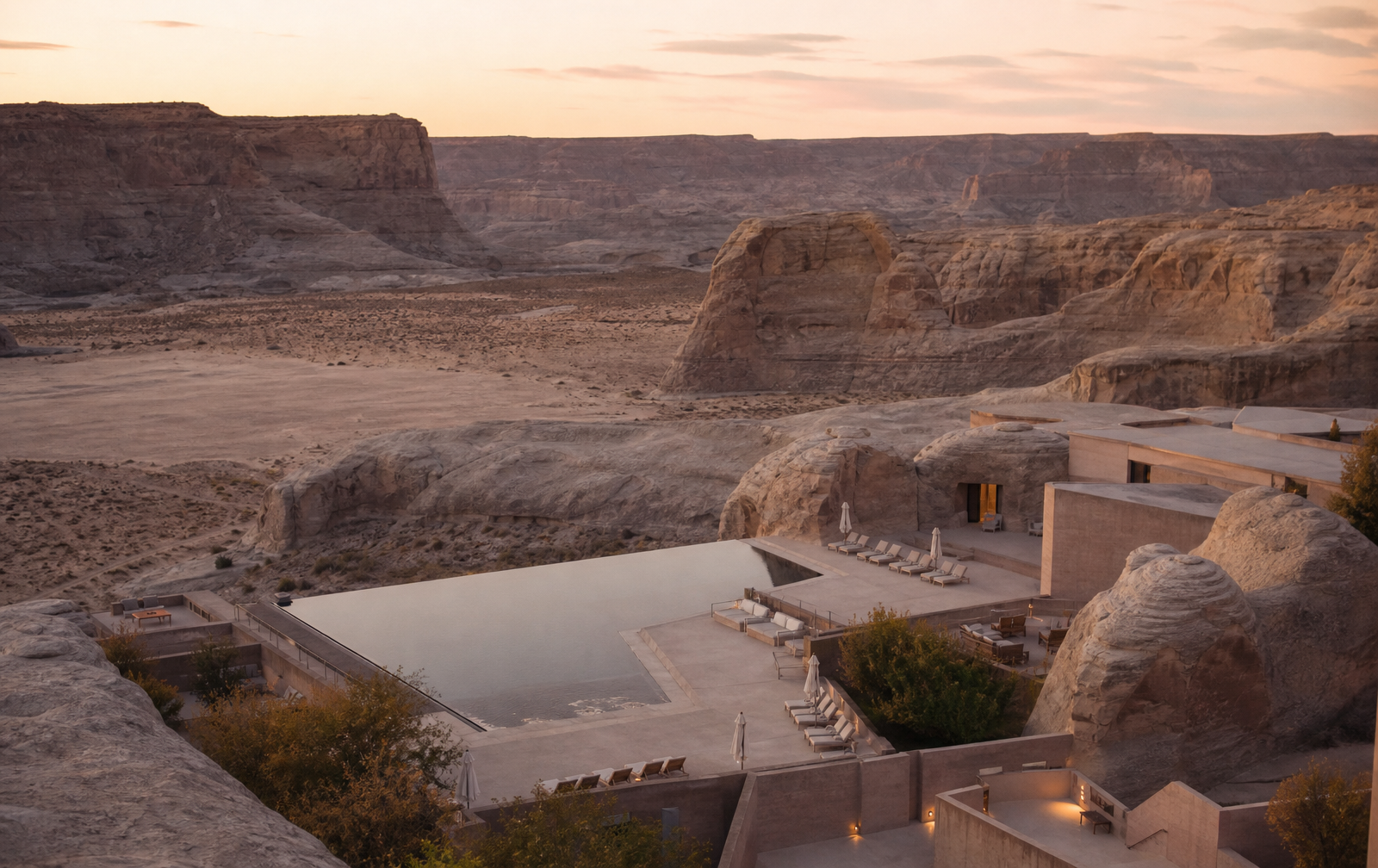 Aerial view of the Amangiri resort in Utah, with a sleek pool set among dramatic desert rock formations at golden hour