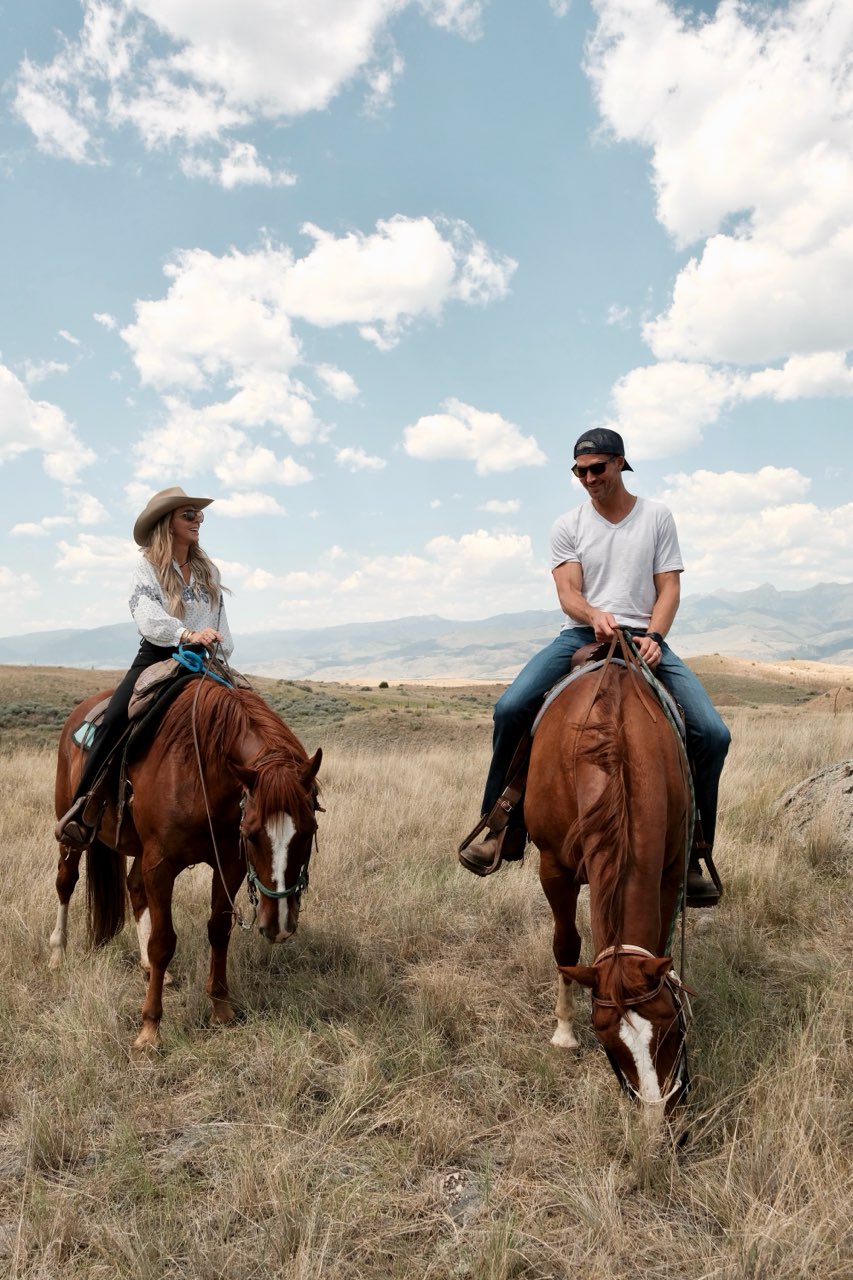 Two riders letting their horses graze in a sage-covered meadow