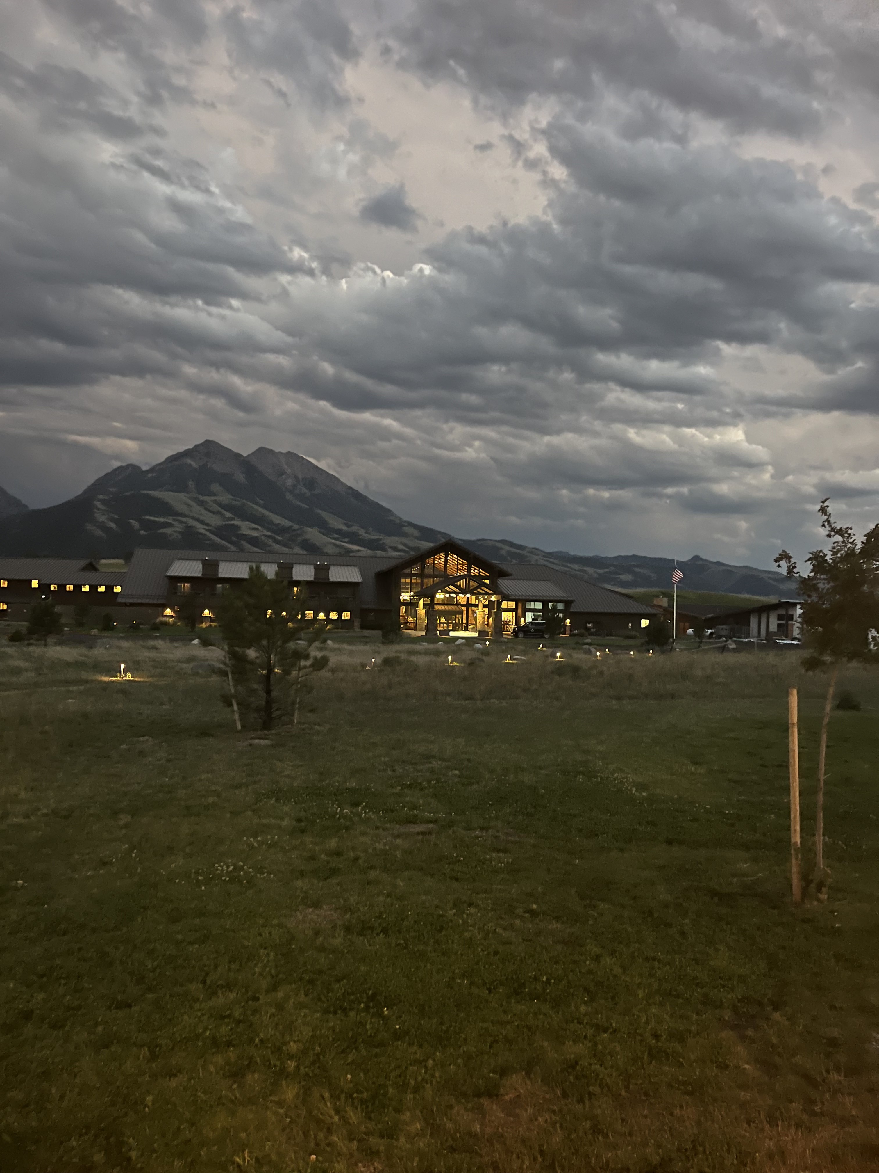 The lodge glowing under a stormy dusk sky with mountains behind